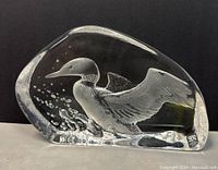 Crystal paperweight with engraved flying loon, showing side view and signature sticker in bottom corner.