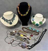 Full view of several necklaces displayed on busts and surface showing assortment and design variety