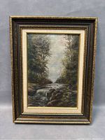 Full view of vintage framed signed oil painting of woodland stream on canvas with ornate dark wood and gold frame