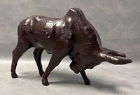 Front right angle view of vintage leather wrapped bull statue, showing muscular detail and horn shape.