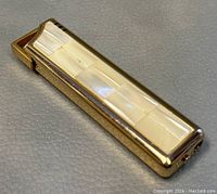 Angle view showing the front mother of pearl inlay and gold-tone edges of the lighter