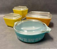 Front view of all five dishes, showing yellow and turquoise colors and clear lids.