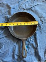 Top view of black cast iron frying pan showing inside cooking surface with measuring tape indicating 8.5 inch diameter.