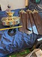 Entire ceiling fan components including brass motor housing, wooden blades, wiring, and mounting plate all laid out on fabric.