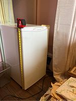 Side view of the white Whirlpool mini fridge showing the height measurement tape indicating approximately 32.5 inches tall.
