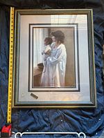 Front side of the large framed picture showing a woman holding a baby, including a measuring tape showing dimensions.