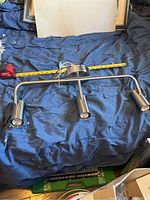 Top view of the three-light ceiling fixture showing the curved metal bar and cylindrical lights, with a tape measure for scale.