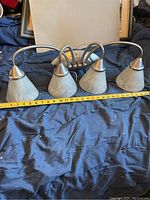 Front view of the four-light wall fixture showing frosted glass bell-shaped shades and metal curved arms.