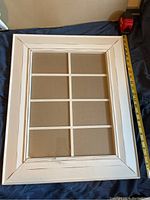 Front view of white wooden picture frame with 8 windowpanes and measuring tape to the side.