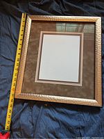 Front view of the rectangular picture frame with hammered metal border and double mat showing the size with measuring tape