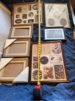 Full view of seven picture frames arranged on blue cloth with measuring tape showing sizes up to about 28 inches