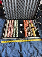 Open aluminum case showing organized poker chips in rows by color and dealer and blind buttons in center