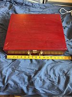 Closed wooden case on fabric with measuring tape showing approximately 16 inches width.