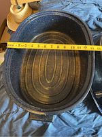 Photo of the large roasting pot with a tape measure inside showing about 14 inches width.
