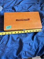 Closed wooden case with Mastercraft logo and measuring tape showing length.