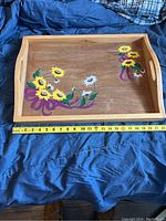 Wooden serving tray shown on blue fabric, measuring tape indicates around 23 inches wide. Tray has hand-painted flowers in yellow, white, purple.