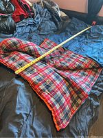 Photo showing the sleeping bag's interior red plaid lining and part of the blue exterior with measuring tape indicating approximately 60 inches length.
