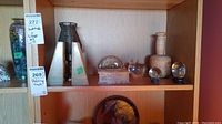 Shelf showing onyx bookends, metal candle holder, glass apple and sphere paperweights, stone box, large wooden pestle