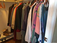 Photo showing hangers with multiple clothing items including jackets, coats, dresses in various colors and styles.