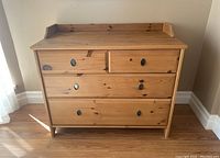 Front view of wooden dresser showing four drawers and metal ring pull handles with visible wood grain and knots.