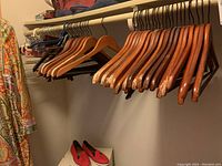 Wooden and plastic clothes hangers on a closet rod, some showing wear and usage marks.