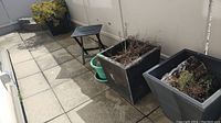 Four composite planters and one folding table on a tiled balcony floor