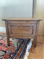 Front view of wood stool or chest showing carved rectangular border detail on the front panel and four straight legs.
