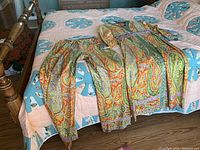 Full view of the tunic and pants laid out on a bed, showing overall pattern and colors.