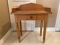 Front view of wooden desk showing drawer and turned legs.