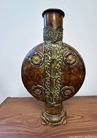 Front view of metal sculpture showing circular floral patterns and vertical central detail