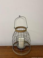 Front view of the metal wire cage candle holder with rope accent and pillar candle inside.