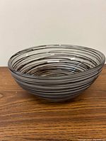 Full side perspective of the 10 inch round decorative bowl showing frosted glass material and black swirl pattern on wood surface.