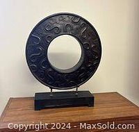 Front view of the dark brown bronze large circular Asian coin sculpture mounted on a rectangular base