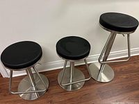 Three stools in a row against a wall showing full lot