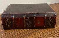 Side view of the storage box showing spine with gold embossed text and decorations.