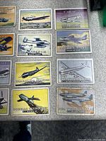 Photo of 12 vintage 1952 Topps airplane trading cards spread on a flat surface. Cards feature military and civilian aircraft such as Il-2 Stormovik, T. Mk 20, D.H. 103 Venom, Hawker P-1081, Saab-90 A-2 and others.