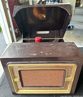 Overall view of the RCA Victoria 1953 record player with the lid open, showing the internal components and worn brown cabinet surface.