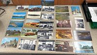 Photo showing all 25 vintage postcards laid out on table, depicting New England landmarks, village scenes, and waterfront views in various color and black and white styles.