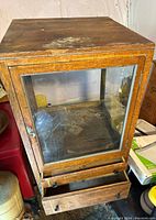 Full view of antique oakwood display cabinet with glass front and two drawers extended below