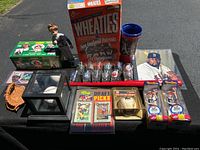Full lot view showing all items including Wheaties box, dolls, shot glasses, baseball glove, photo, and display cases.