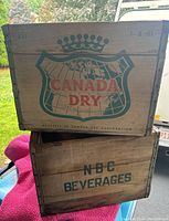 Canada Dry branded wooden crate stacked on top of crate marked NBC Beverages
