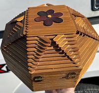 Top and side view of an octagonal sewing basket made entirely of natural wood popsicle sticks with a flower decoration on top.
