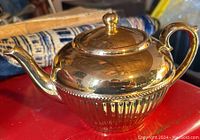 Side view of gold Gibson teapot showing fluted body design, handle, and spout.