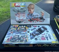 Opened box showing arrangement of race car, figures, tires and accessories still in original compartments.