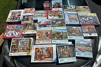 Wide view of 23 puzzle boxes laid out, showing variety of themes and puzzle sizes