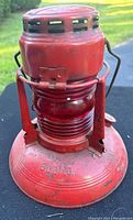 Front view of the red railroad lantern showing vent holes at the top and red glass globe in center