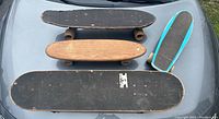 Four skateboards photographed from above showing various shapes, sizes, and wear conditions.