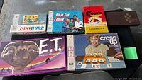 Lot of six vintage board games including Password, All in the Family, Cross Up, Cootie, E.T. board games, and a brown magnetic chess set box.