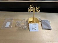 Four 18K gold plated rings on a golden tree-shaped ring stand, with a small gray pouch and plastic bags in the background.