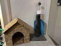 Full view of woven cat house and tall scratching post with pom pom toy.